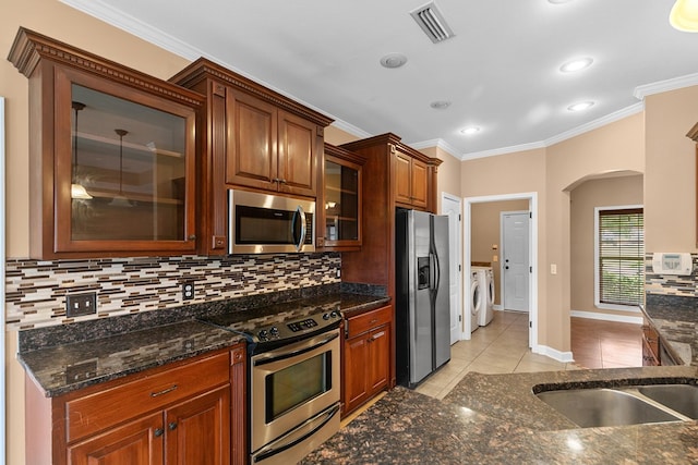 170 County Road 751, Enterprise, AL 36330 - kitchen with stainless steel appliances, arched walkways, backsplash, crown molding, and light tile patterned floors