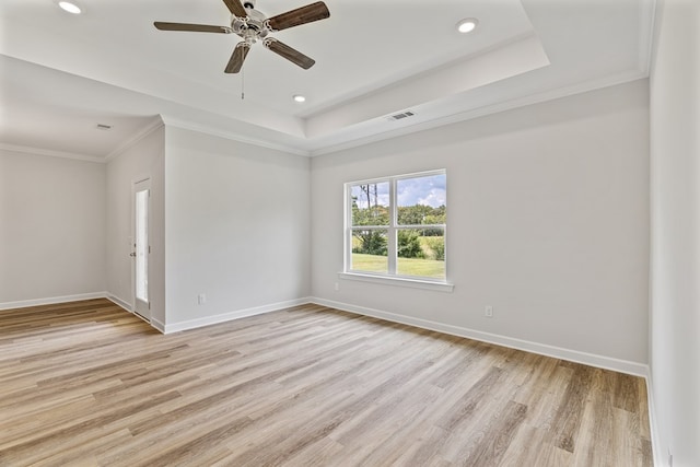 empty room with a raised ceiling, ceiling fan, light hardwood / wood-style flooring, and crown molding