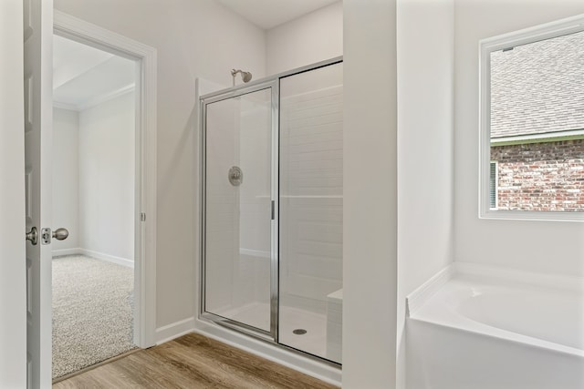 bathroom with hardwood / wood-style flooring and shower with separate bathtub