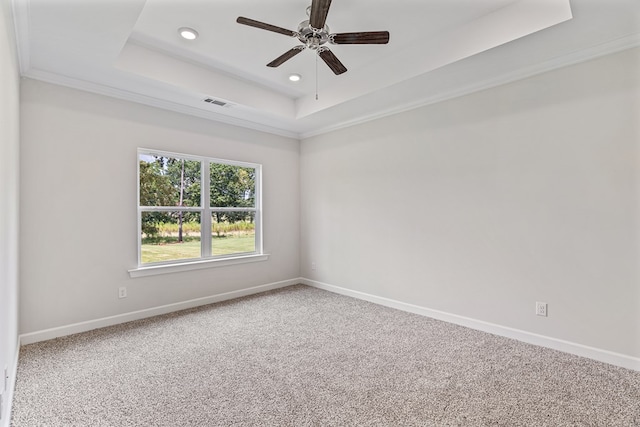 carpeted spare room with a raised ceiling, ceiling fan, and crown molding