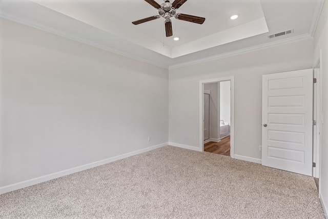 interior space with crown molding, ensuite bath, carpet flooring, ceiling fan, and a tray ceiling