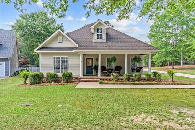 view of front of home with a shingled roof, covered porch, and a front yard