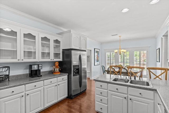 kitchen with stainless steel fridge, a sink, white cabinetry, and glass insert cabinets