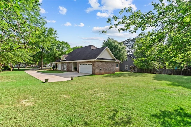 view of yard with a garage, fence, and driveway