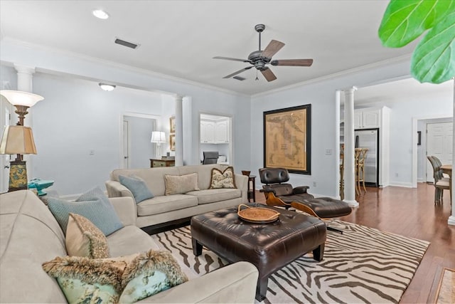 living area with ornamental molding, a ceiling fan, ornate columns, visible vents, and dark wood-style floors