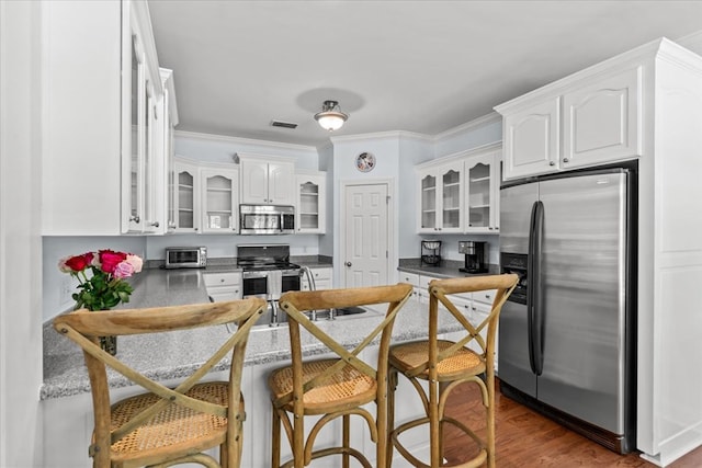 kitchen with crown molding, appliances with stainless steel finishes, white cabinetry, visible vents, and glass insert cabinets