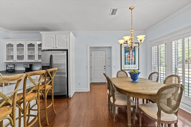 dining room featuring visible vents, dark wood finished floors, baseboards, a notable chandelier, and ornamental molding