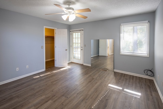 spare room with a textured ceiling, plenty of natural light, and dark wood-type flooring