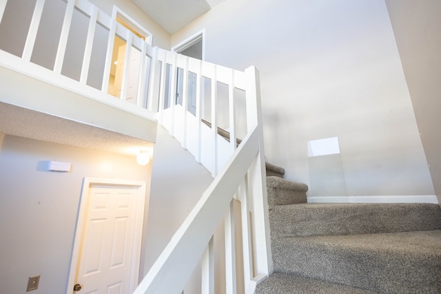 stairway featuring a towering ceiling and carpet