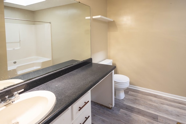 full bathroom featuring hardwood / wood-style floors, vanity, bathing tub / shower combination, a skylight, and toilet