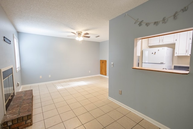 unfurnished living room featuring ceiling fan, light tile patterned flooring, and a textured ceiling