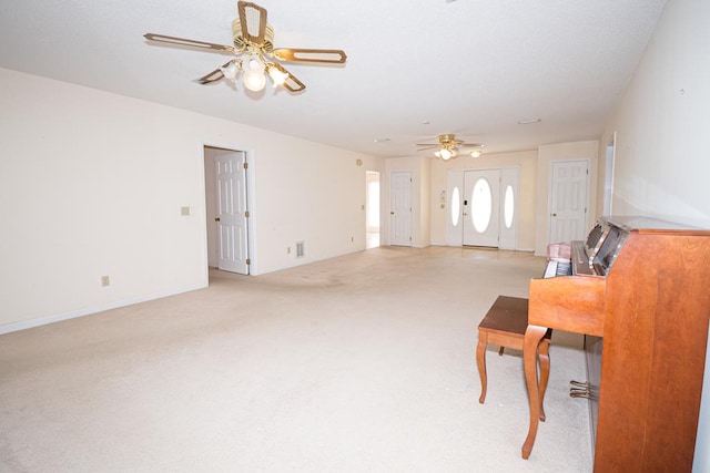 interior space with a ceiling fan, light carpet, and baseboards