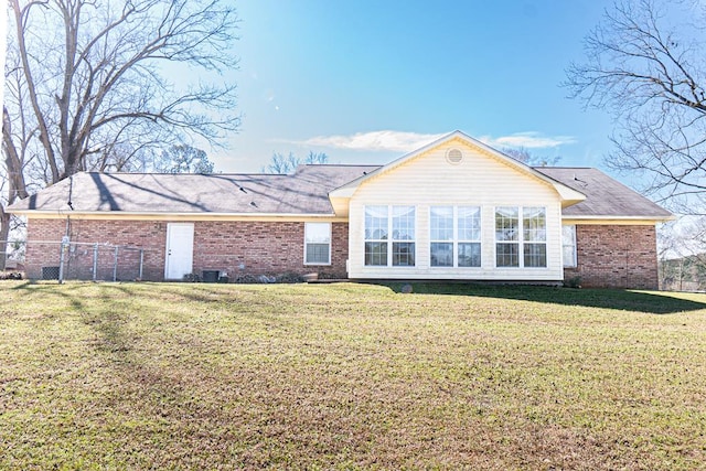 back of property featuring a yard, fence, and brick siding