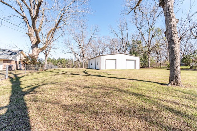view of yard featuring driveway, a detached garage, an outbuilding, a pole building, and fence
