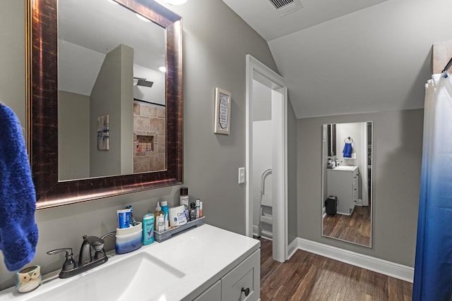 bathroom with vanity, hardwood / wood-style flooring, and lofted ceiling