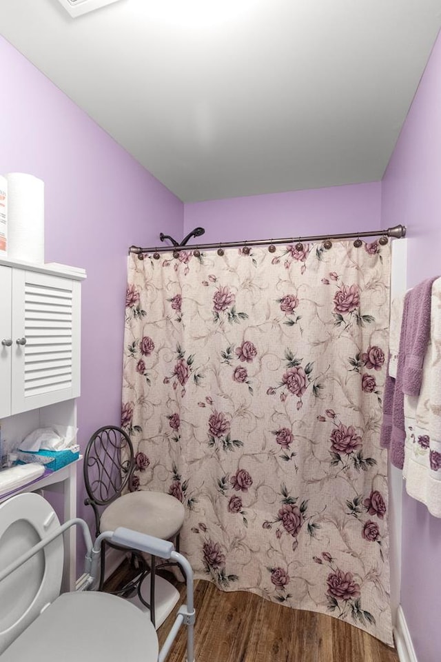 bathroom featuring a shower with shower curtain, hardwood / wood-style flooring, and toilet