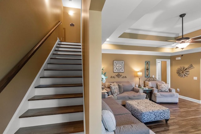 stairway featuring ceiling fan, wood-type flooring, and crown molding