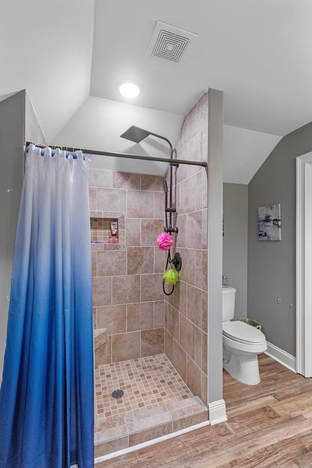 bathroom featuring curtained shower, hardwood / wood-style floors, vaulted ceiling, and toilet