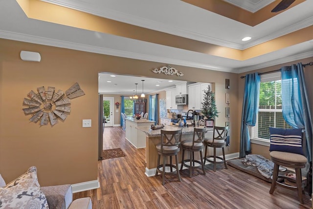 bar with pendant lighting, white cabinetry, crown molding, and wood-type flooring