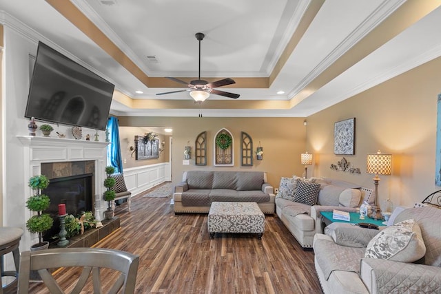 living room featuring ceiling fan, dark hardwood / wood-style flooring, ornamental molding, and a tray ceiling