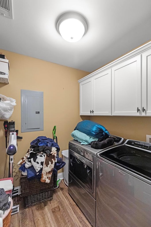 laundry area featuring cabinets, light wood-type flooring, electric panel, and washing machine and clothes dryer