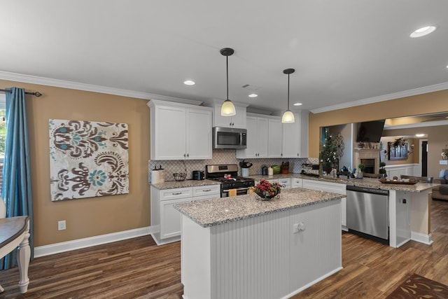 kitchen featuring appliances with stainless steel finishes, dark wood-type flooring, pendant lighting, white cabinets, and a center island