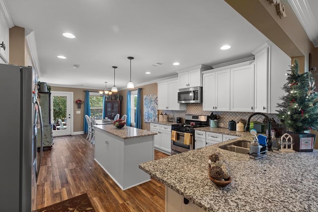 kitchen with white cabinets, crown molding, a kitchen island, dark hardwood / wood-style flooring, and stainless steel appliances