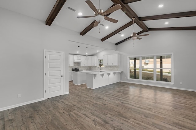 unfurnished living room with ceiling fan, beamed ceiling, dark hardwood / wood-style floors, and high vaulted ceiling