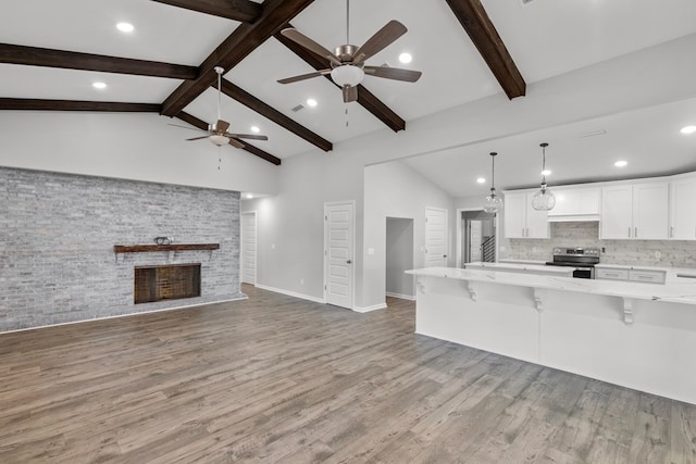 kitchen with a kitchen breakfast bar, stainless steel electric stove, pendant lighting, hardwood / wood-style flooring, and white cabinets