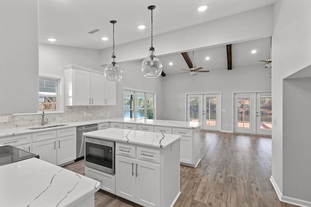 kitchen featuring white cabinetry, a kitchen island, built in microwave, and a healthy amount of sunlight