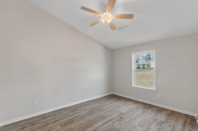 empty room with ceiling fan, hardwood / wood-style floors, and vaulted ceiling