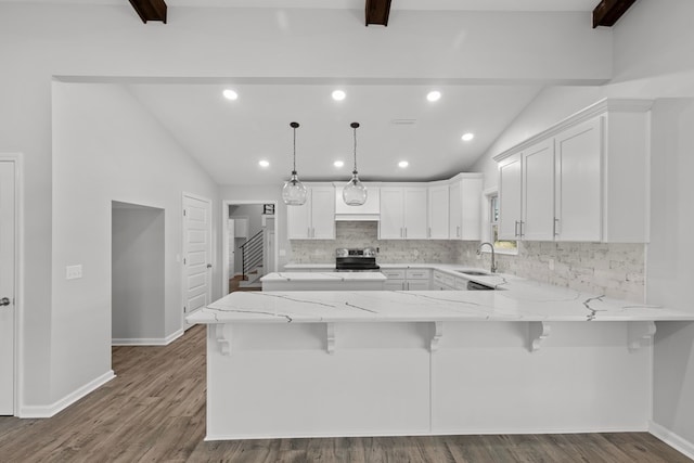 kitchen featuring sink, lofted ceiling with beams, decorative light fixtures, a kitchen bar, and white cabinets