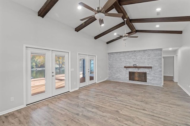 unfurnished living room featuring ceiling fan, french doors, beamed ceiling, light hardwood / wood-style floors, and a fireplace