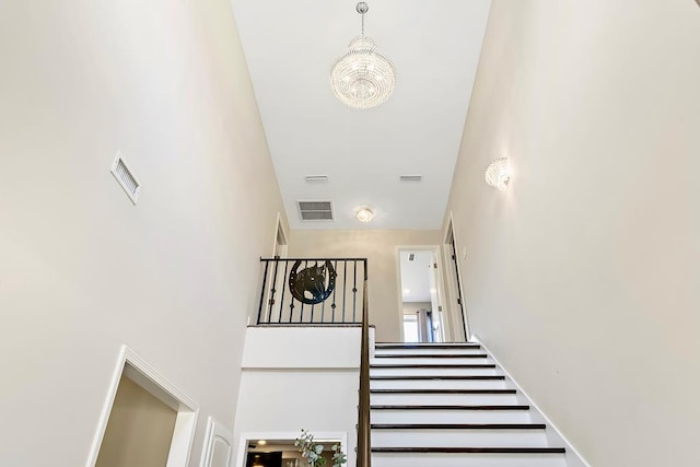 stairway featuring a towering ceiling and a notable chandelier