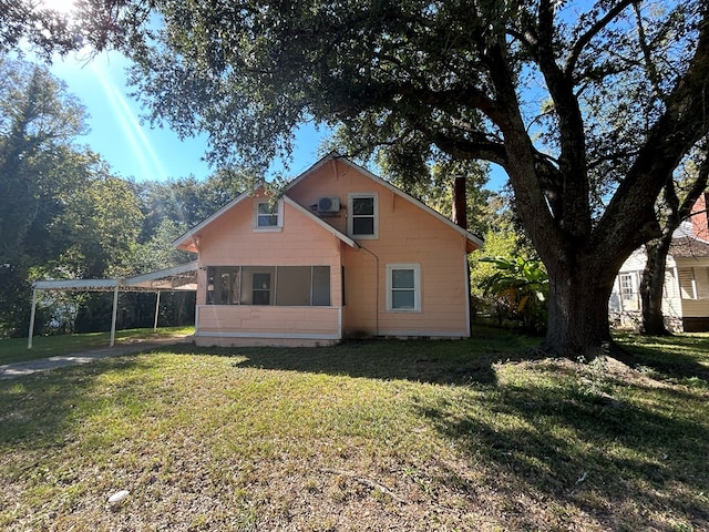 rear view of property featuring a carport and a lawn