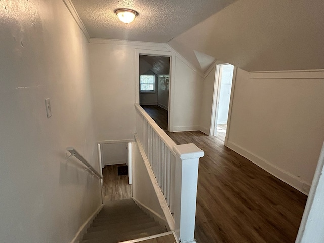 stairs with wood-type flooring, a textured ceiling, and vaulted ceiling