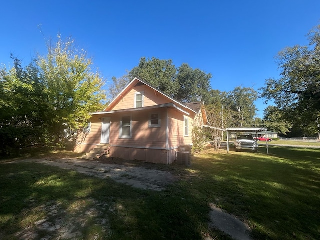 view of side of home with a carport and a lawn