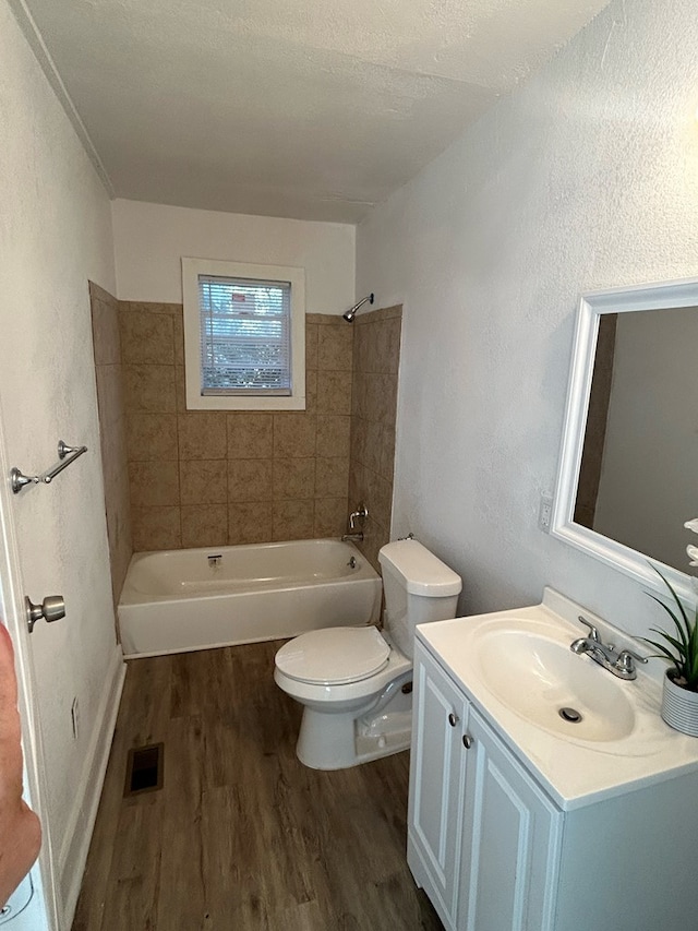 full bathroom with vanity, tiled shower / bath, hardwood / wood-style flooring, toilet, and a textured ceiling