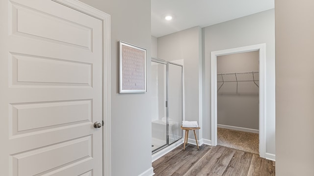 bathroom with hardwood / wood-style flooring and a shower with door