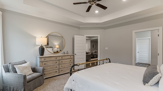 carpeted bedroom featuring ceiling fan, a raised ceiling, and ornamental molding