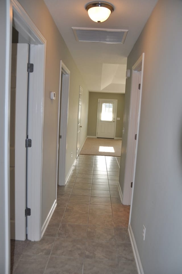 corridor featuring visible vents, tile patterned flooring, and baseboards