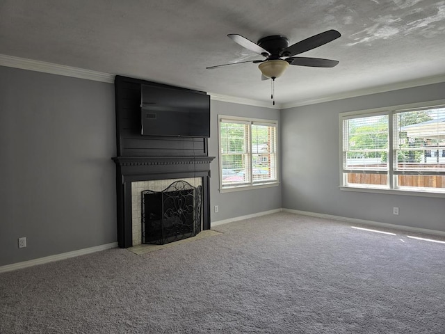 unfurnished living room featuring carpet floors, a large fireplace, ceiling fan, baseboards, and crown molding