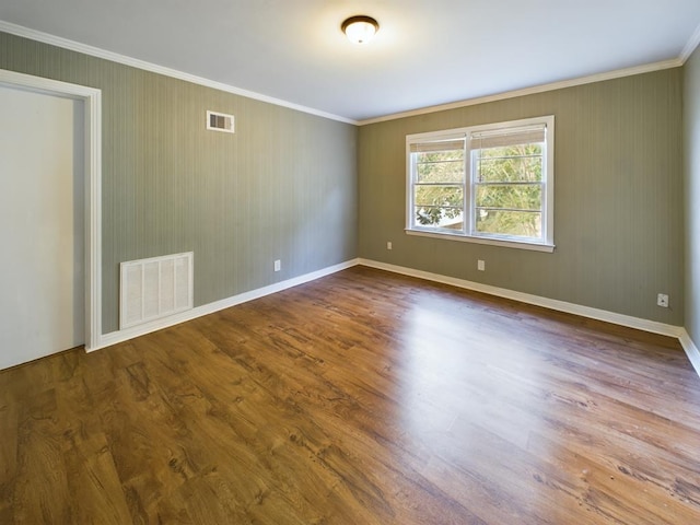 spare room featuring visible vents, ornamental molding, and wood finished floors