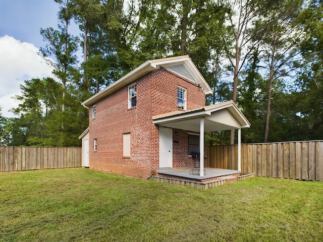 rear view of property with brick siding, a fenced backyard, and a yard