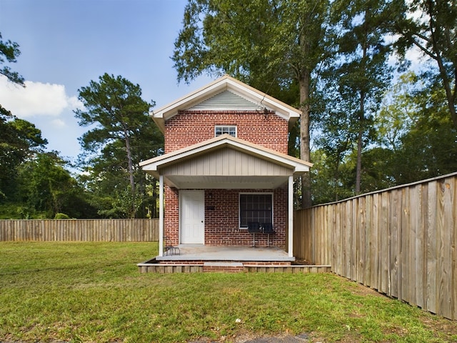 view of front of house with a front lawn, brick siding, and a fenced backyard