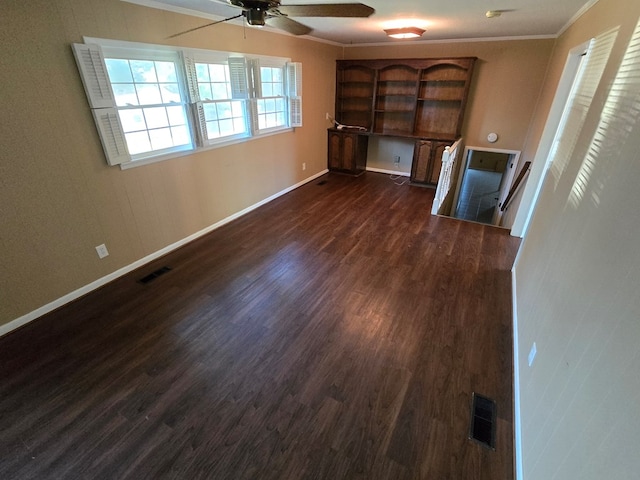 unfurnished living room with dark hardwood / wood-style floors, ceiling fan, built in desk, and crown molding