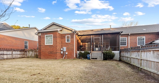 rear view of house featuring a lawn and a sunroom