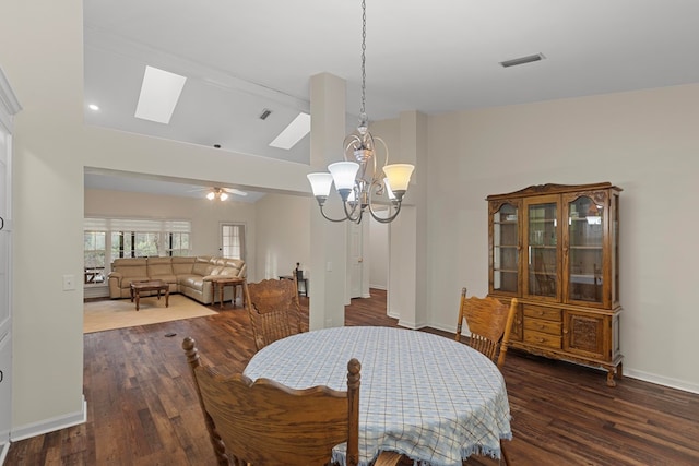 dining space featuring ceiling fan with notable chandelier, vaulted ceiling with skylight, and dark hardwood / wood-style floors