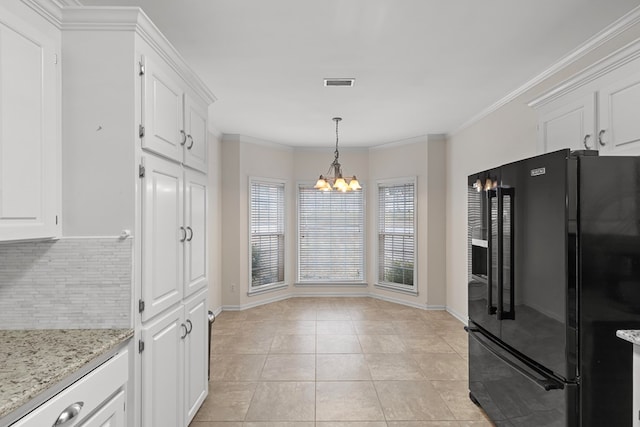 kitchen with light stone countertops, a chandelier, black fridge, light tile patterned floors, and white cabinetry