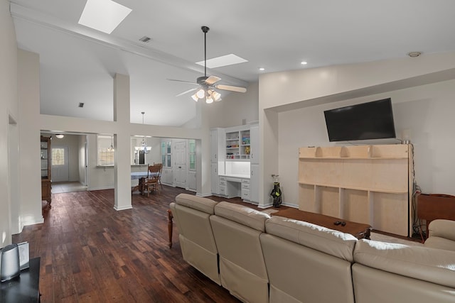 living room with ceiling fan with notable chandelier, dark wood-type flooring, high vaulted ceiling, and a skylight